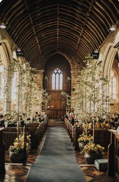 a church filled with lots of pews covered in flowers and greenery on either side of the aisle