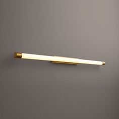 a bathroom wall light that is on the side of a gray wall with a gold handle