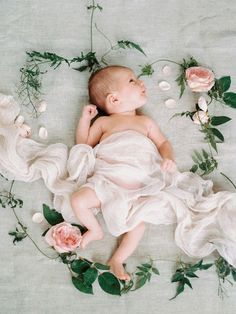 a baby laying on top of a bed covered in flowers