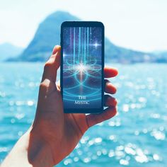 someone is holding up their cell phone to take a photo with the ocean in the background