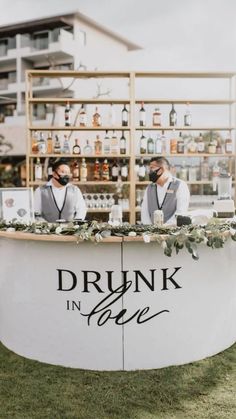 two men standing behind a bar that says drunk in love