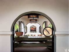 an archway leading into a dining room with a clock on it's wall and other furniture in the background