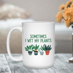 a white coffee mug sitting on top of a table next to a vase filled with flowers