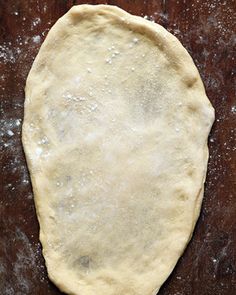 an uncooked pizza dough sitting on top of a wooden table