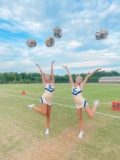 two cheerleaders are jumping in the air with pom - poms on their heads