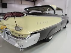 an old yellow and gray car parked in a garage