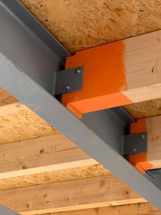 an orange beam is attached to the side of a wooden structure with metal brackets on it