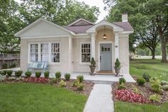 a white house with green grass and trees in the front yard, along with landscaping