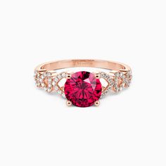 a pink ring with diamonds on the side and an oval shaped ruby stone in the center