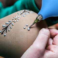 a person using a small tool to decorate a vase