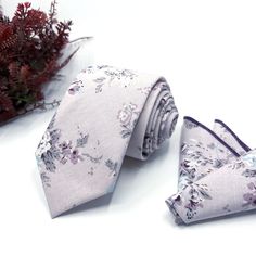 two ties are sitting next to each other on a white surface with red flowers in the background