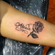 a rose tattoo on the arm that says,'alenia'and is in black ink