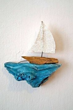 a small wooden sailboat floating on top of a blue wave in the ocean next to a white wall