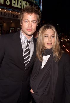 a man and woman standing next to each other in front of a building at night