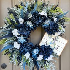 a wreath with blue flowers and greenery is hanging on the front door to welcome guests