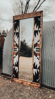 a mirror sitting on the ground next to a metal structure with an arrow design in it