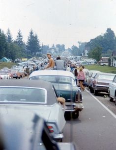 people are standing on the back of cars in a parking lot with many parked cars