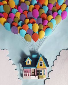 a paper house floating in the air with balloons