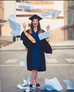 a woman in graduation cap and gown throwing papers into the air