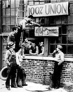 an old black and white photo of men hanging from the side of a brick building