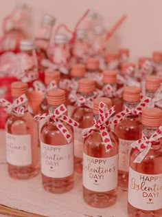 several bottles of pink liquid with red and white bows on them sitting on a table