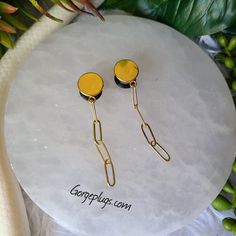 pair of yellow earrings on white plate with flowers in background