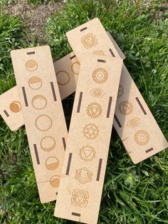 three cardboard bookmarks sitting on top of green grass in the middle of two rows