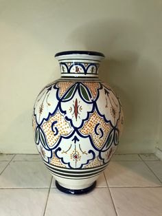 a large blue and white vase sitting on top of a tile floor next to a wall