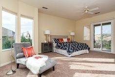 a bedroom with a large bed, chair and sliding glass doors leading to a balcony