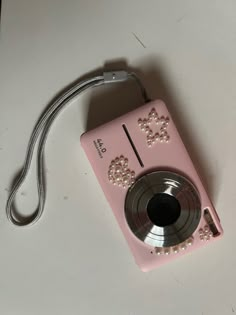 a pink camera sitting on top of a white table next to a corded phone