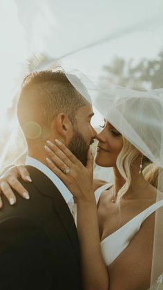 a bride and groom kissing under the veil