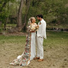 a bride and groom are standing in the grass