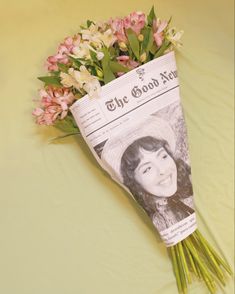 a bouquet of flowers sitting on top of a green table next to a news paper