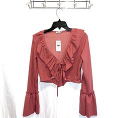 Stand Out In A Sophisticated Number With This Long-Sleeved Ruffle Frill Top. Featuring A Plunge Neckline With Tie Detailing, This Sassy Crop Is The Perfect Choice For A Classy Night Out. Pair With A Bodycon Midi Skirt And Heels To Complete The Elegant Look. Rose Pink / Mauve Pink Long Sleeve Ruffle/Frill Details Around Neckline And On Sleeves Cropped Plunge Neckline Tie Feature On Bust 96% Polyester 4% Spandex Spring Night Out Blouse With Ruffle Hem, Spring Ruffle Hem Blouse For Night Out, Spring Date Night Blouse With Ruffles, Feminine Ruffled Tops For Date Night, Feminine Ruffled Blouse For Date Night, Flirty Long Sleeve Blouse For Spring, Spring Blouse With Ruffles For Night Out, Ruffled Blouse For Night Out In Spring, Fall Night Out Tops With Ruffles