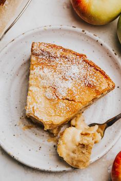 a piece of pie on a white plate with a fork and some fruit next to it