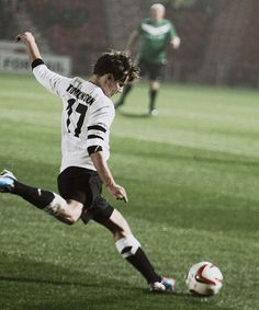 a young man kicking a soccer ball across a field