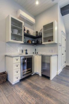 an empty kitchen with white cabinets and wood flooring on the walls is pictured in this image