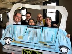 a group of people standing in front of a car made out of paper