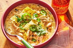 a bowl of soup with tortilla chips and green peppers next to a glass of beer