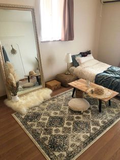 a bedroom with a bed, mirror and rug on the floor in front of it