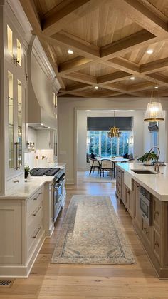 a large kitchen with wooden ceiling and white cabinets, along with an area rug on the floor