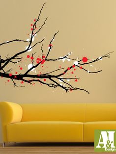 a living room with a yellow couch and a tree branch painted on it's wall