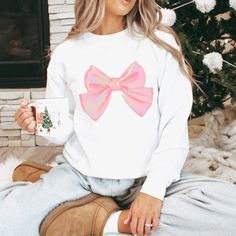 "Introducing the Pink Bow Oversized Crewneck Sweatshirt: Super Cozy AND Trendy! The Power of Pink Bows: Step into a world of sweetness with our Pink Bow Oversized Crewneck Sweatshirt. It's not just a sweatshirt; it's a celebration of charm, letting everyone know \"I AM the gift\"! Why Choose Our Pink Bow Sweatshirt? Perfectly Cozy: Made from a medium-heavy fabric blend of 50% cotton and 50% polyester, this sweatshirt doesn't just feel super soft and cozy; it's an invitation to snuggle during those chilly months.  Pair it with a pair of leggings and uggs and head out for a day of shopping or with pj pants for sleepovers with your besties! Durability Redefined: Created with direct-to-garment printing to insure the most crisp, vibrant and long lasting image, our soft and cozy sweatshirts stan Cute Winter Sweatshirt For Gift, Cute Winter Sweatshirt Gift, White Casual Sweatshirt For Holidays, Casual White Sweatshirt For Holidays, Casual White Holiday Sweatshirt, Pink Cotton Holiday Sweatshirt, Cute White Crew Neck Sweater, Cozy Sweatshirt As A Gift, Cozy Long Sleeve Sweatshirt For Gift