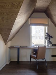 a chair sitting in front of a window next to a desk with a lamp on it