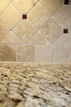 a marble counter top in a kitchen next to a tile backsplash with brown grouting