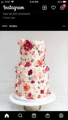 a three tiered wedding cake with pink and red flowers on the top, sitting on a white pedestal