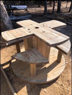 a bench made out of wooden boards sitting on top of a pile of dirt next to a tree