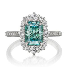 an emerald colored diamond surrounded by white diamonds