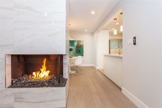 a fireplace in the middle of a living room with wood flooring and white walls