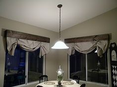 a dining room table with four chairs in front of two windows